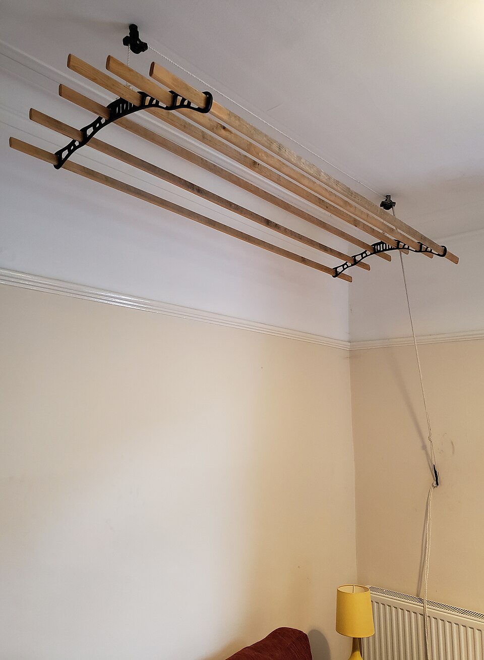 A wooden pulley clothes airer fixed to a ceiling