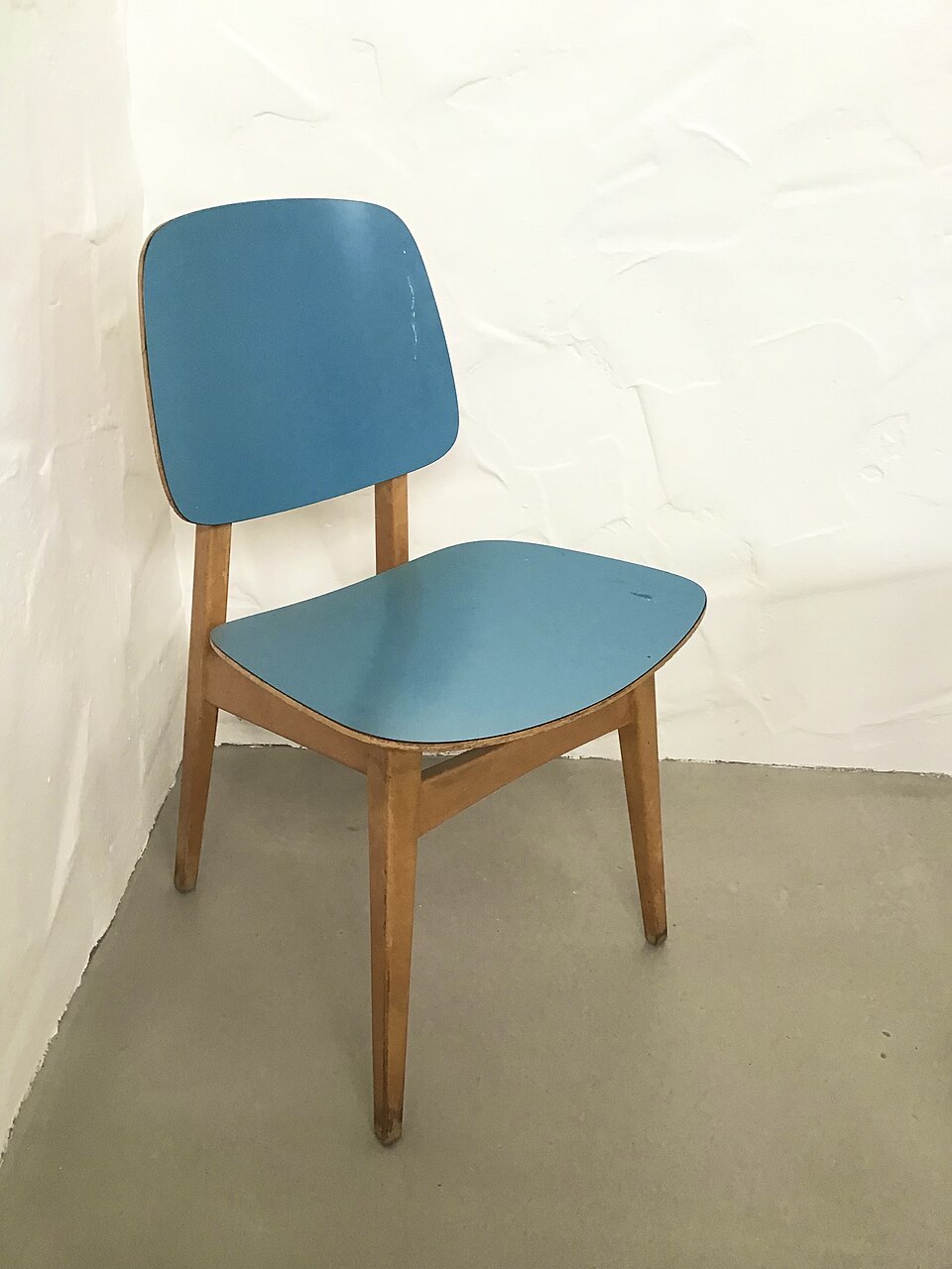 A mid-century wooden kitchen chair with a blue seat