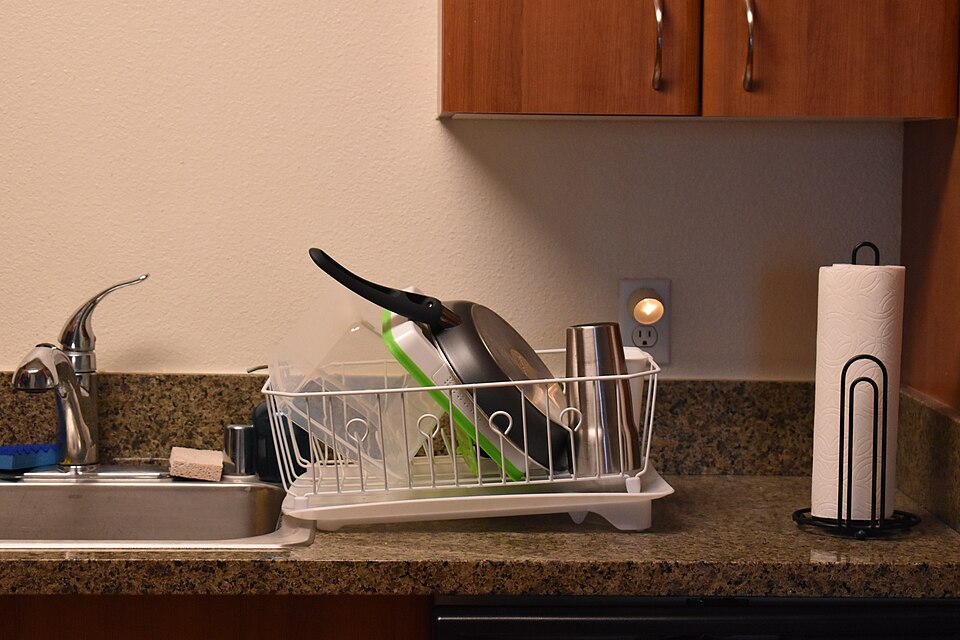 A wire dish rack beside a kitchen sink