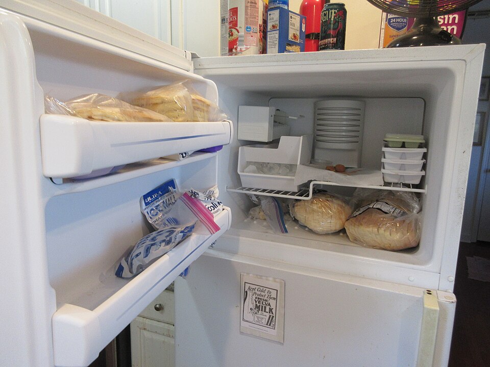 An open fridge freezer with food on the door shelves