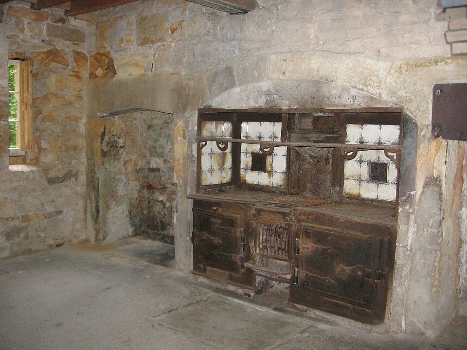 A rusting cast-iron kitchen range in a stone chimney recess