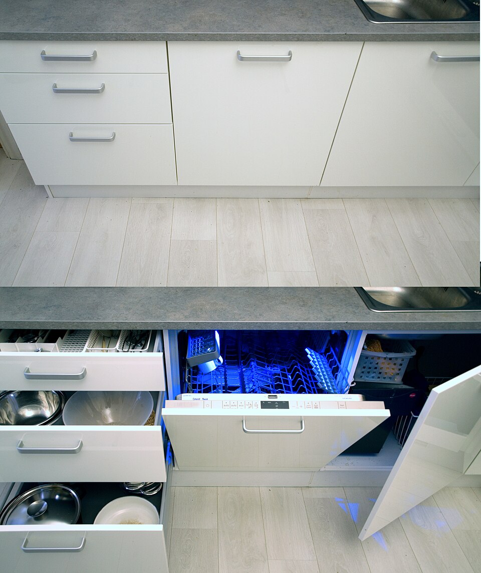 An integrated dishwasher open beneath a kitchen worktop