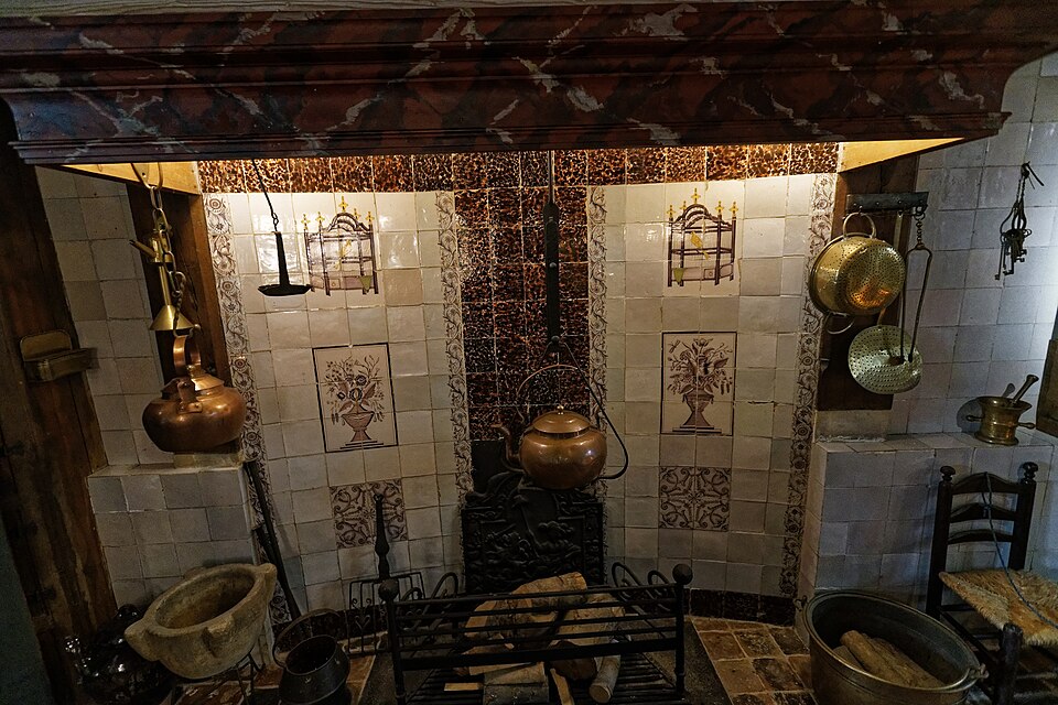 A historic kitchen with tiled walls around the hearth