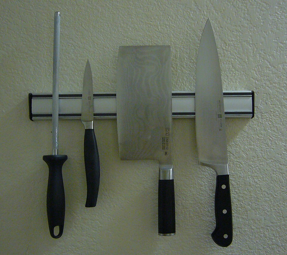 A magnetic knife rack holding a cleaver and three knives