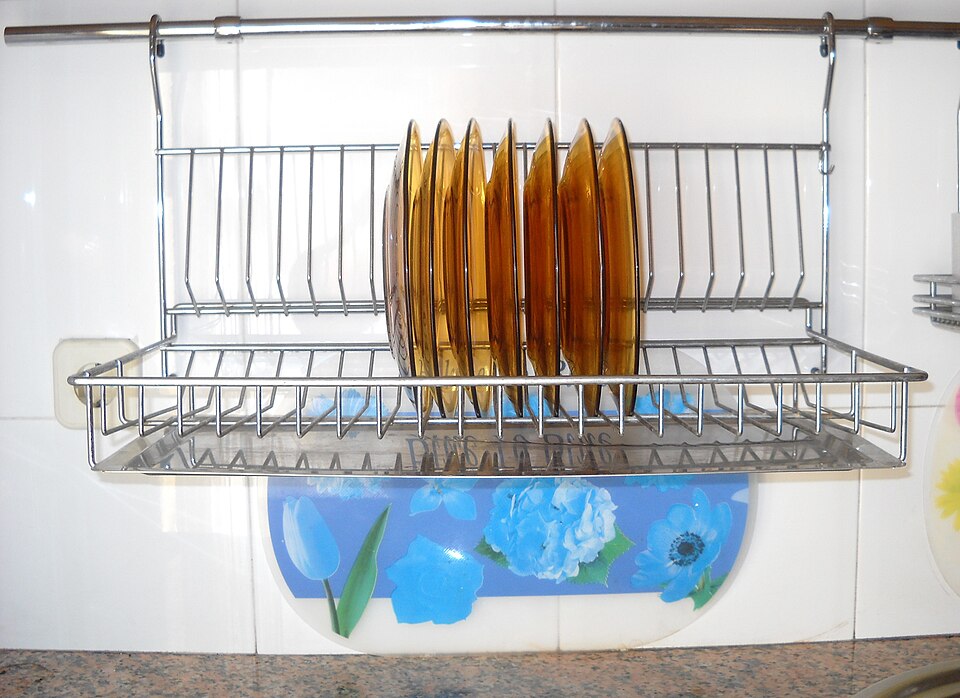 A wall-mounted rack drying a row of plates above a sink