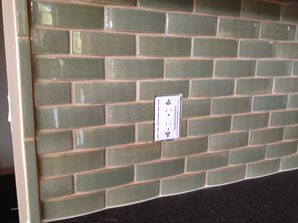 A splashback of green glazed brick-shaped tiles
