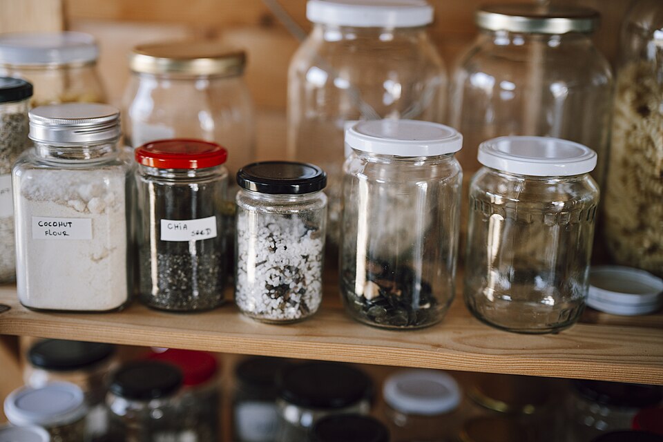 Glass storage jars of dry food on a pantry shelf
