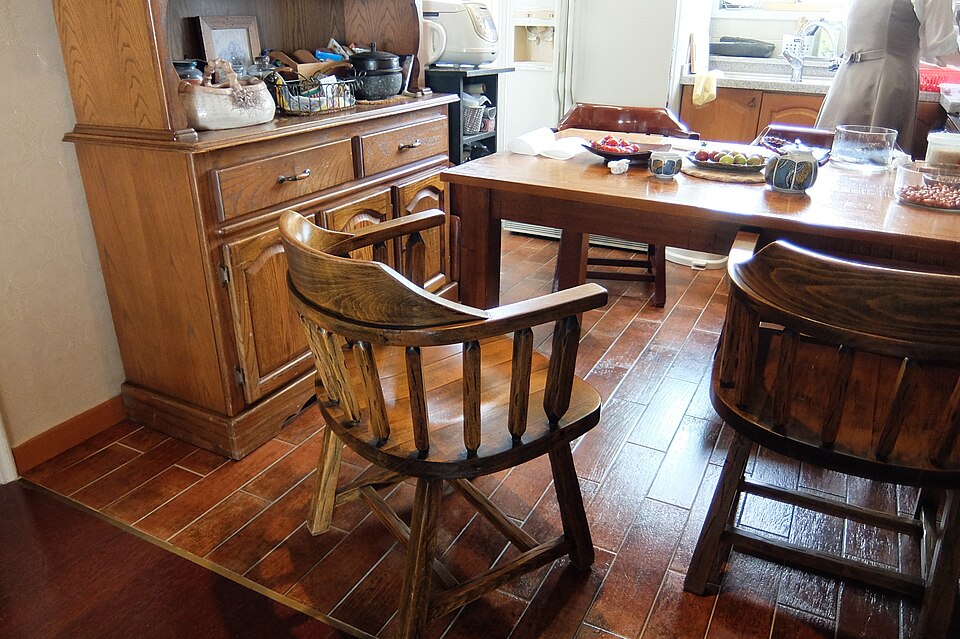 A kitchen with a wooden cupboard, table and spindle-back chairs