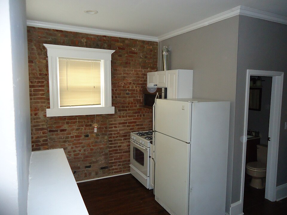 A small kitchen with a single window in a brick wall