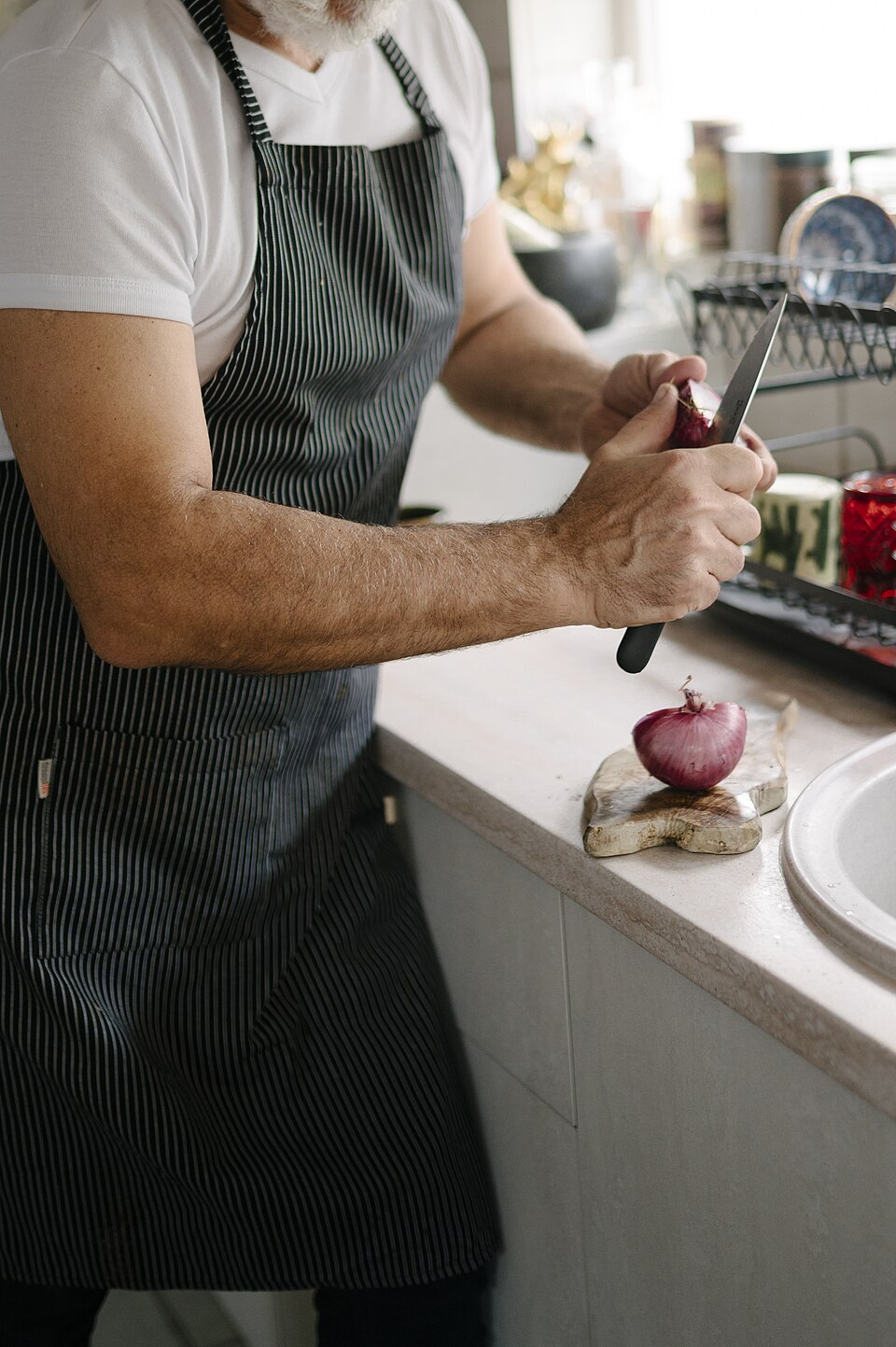 A cook chopping an onion at a kitchen counter