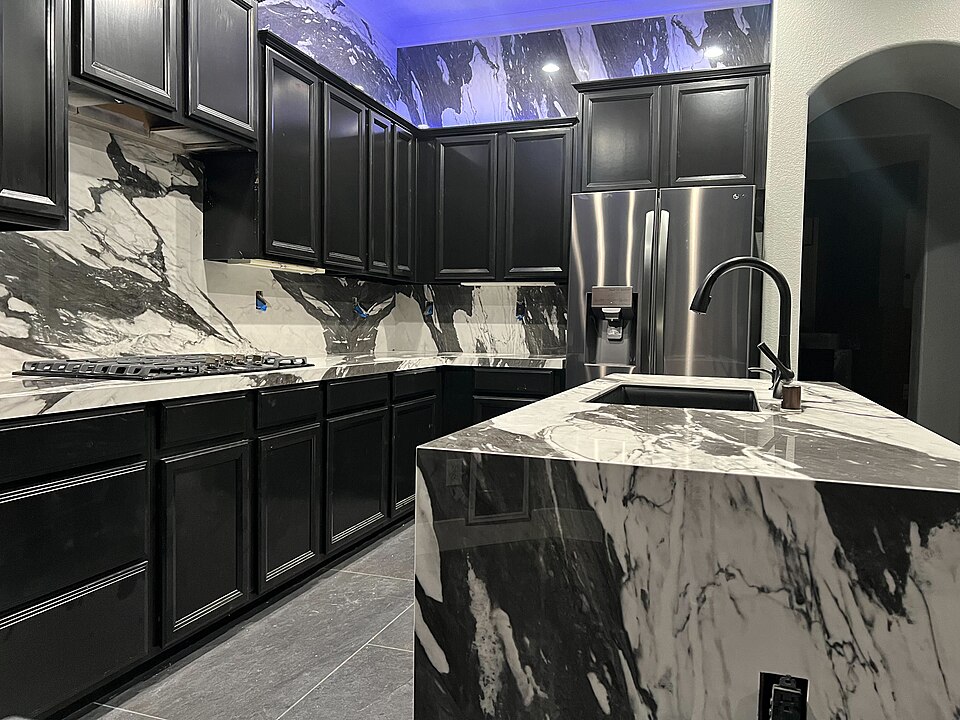 A kitchen island with a bold marble-effect worktop and dark cabinets