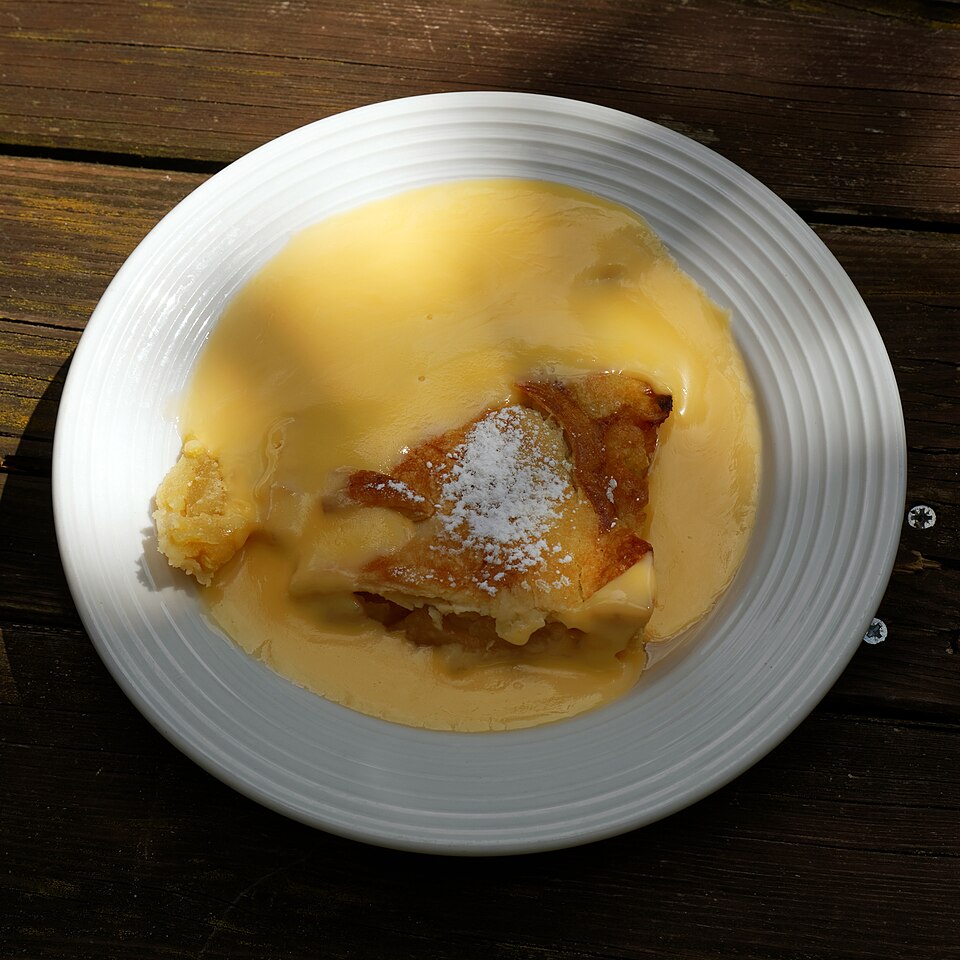 A slice of apple pie served with custard
