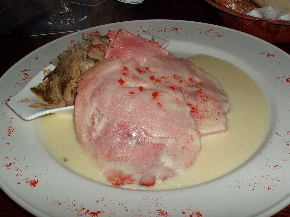 Sliced boiled bacon with cabbage and a creamy white sauce