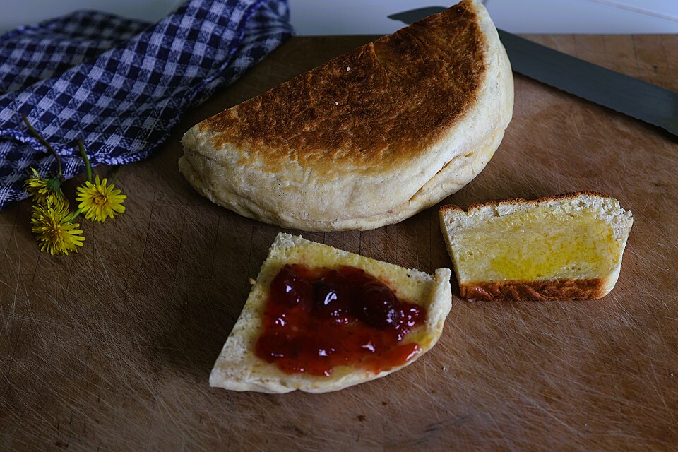 A round of bara planc, Welsh bakestone bread, split and spread with butter and jam