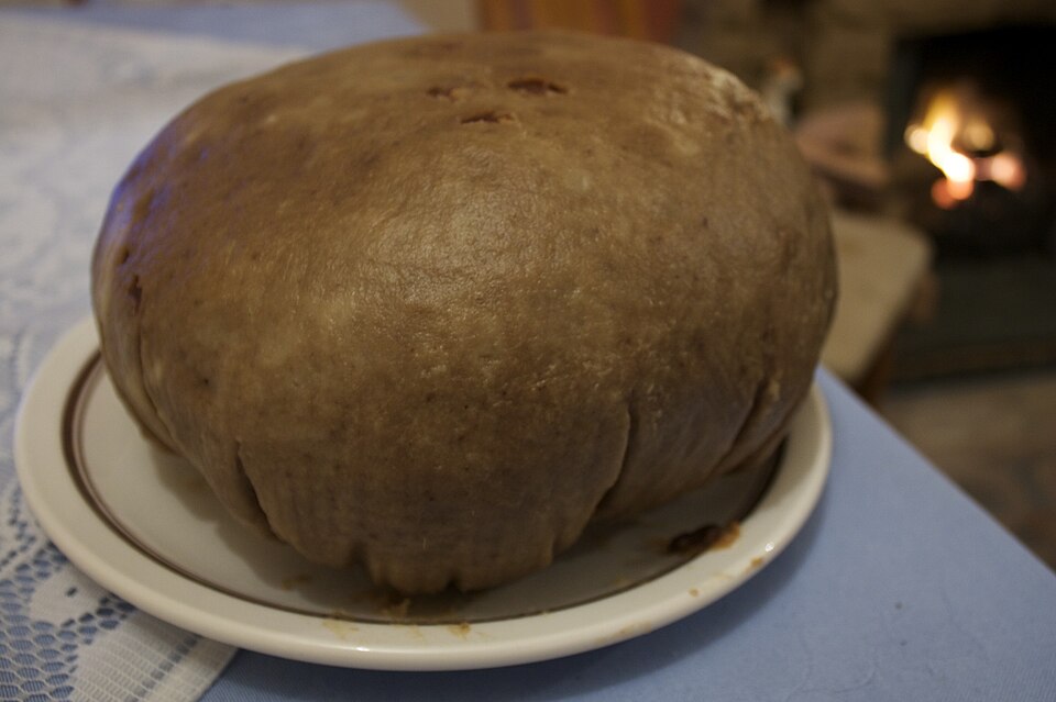 A round, dark clootie dumpling on a plate