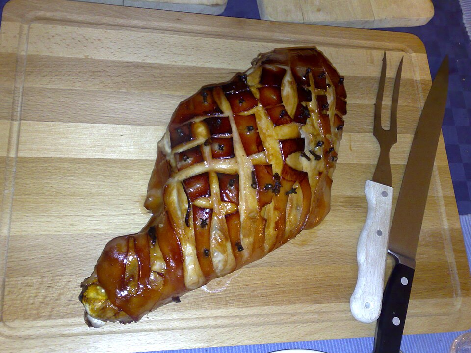 A honey-glazed ham scored in a diamond pattern on a carving board