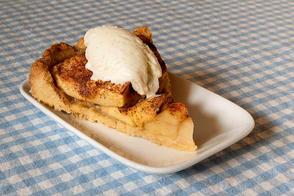 A slice of apple cake with vanilla ice cream