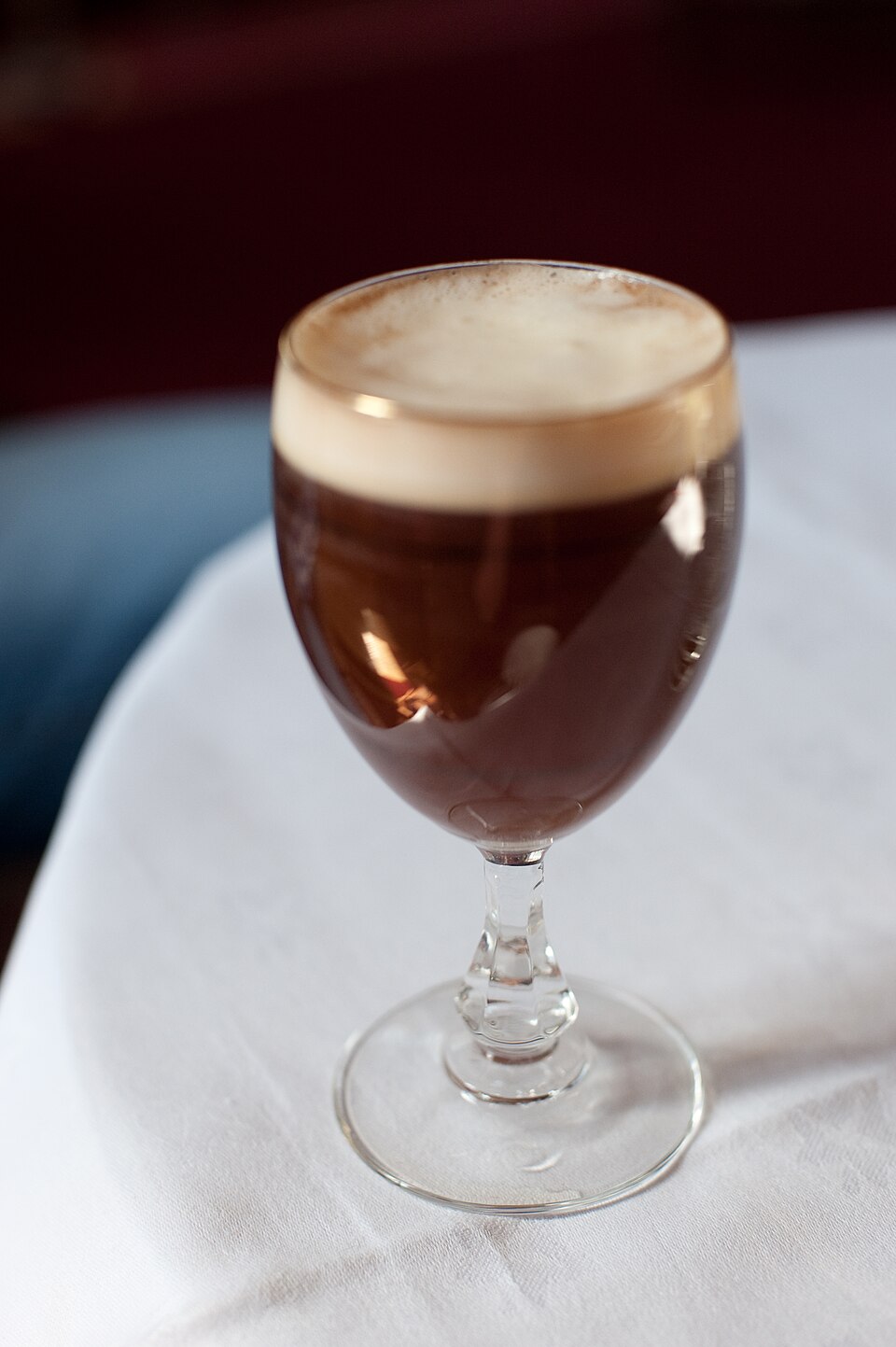 An Irish coffee in a stemmed glass, topped with a layer of cream