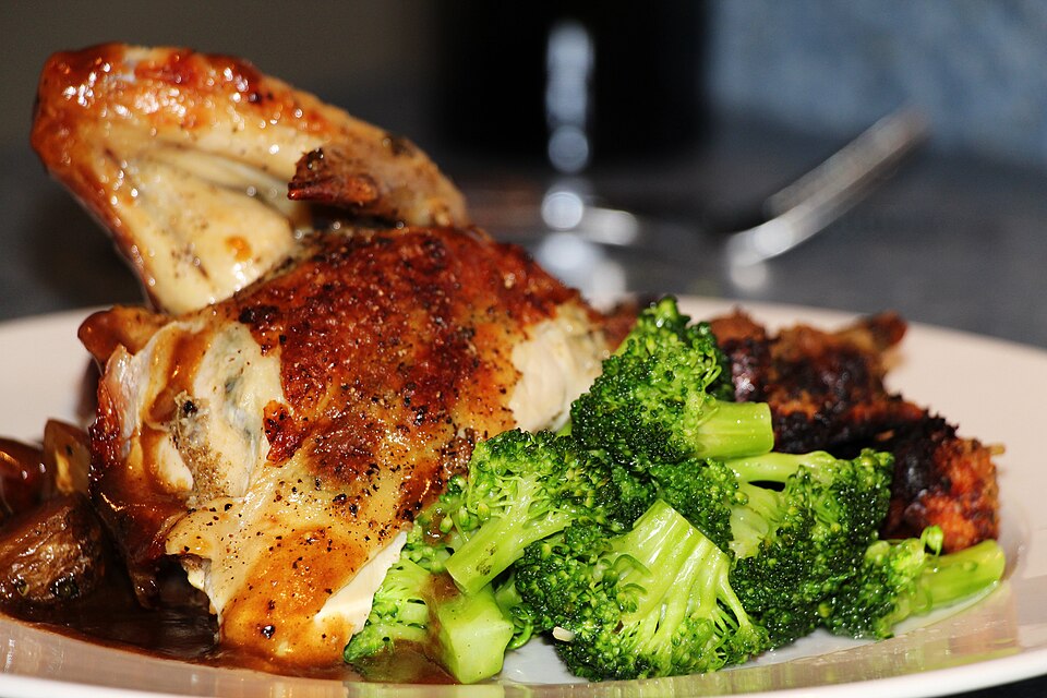 A roast chicken dinner plate with broccoli and gravy