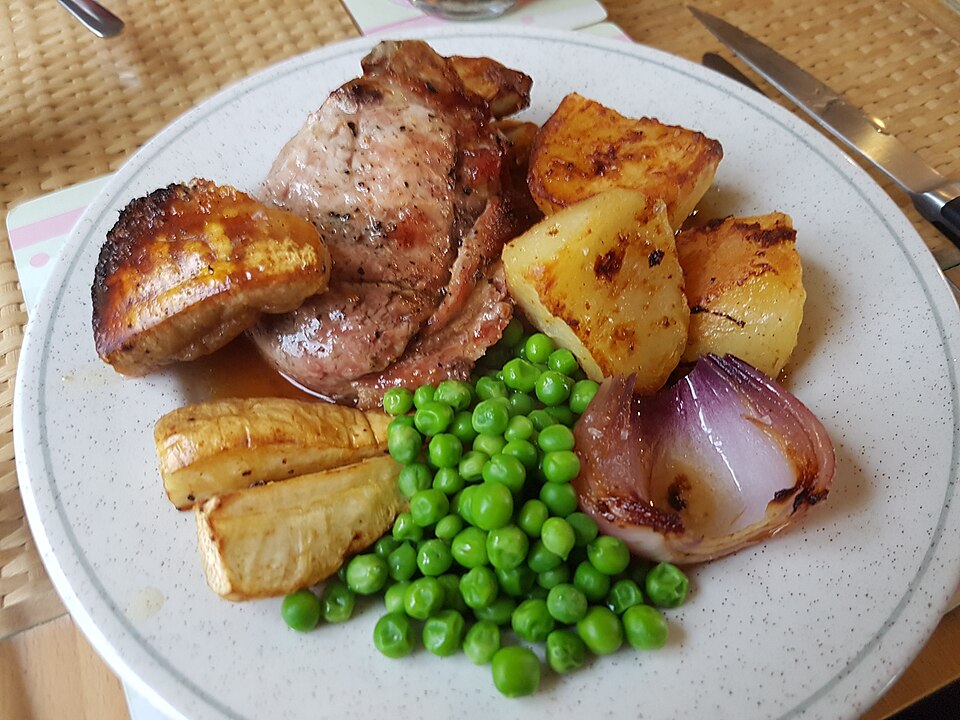 Roast pork and crackling with roast potatoes, parsnips and peas