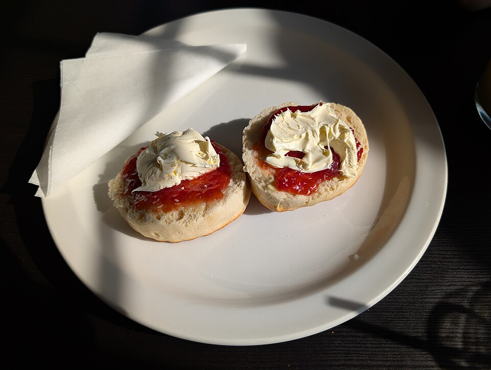 Scones split and topped with clotted cream and strawberry jam