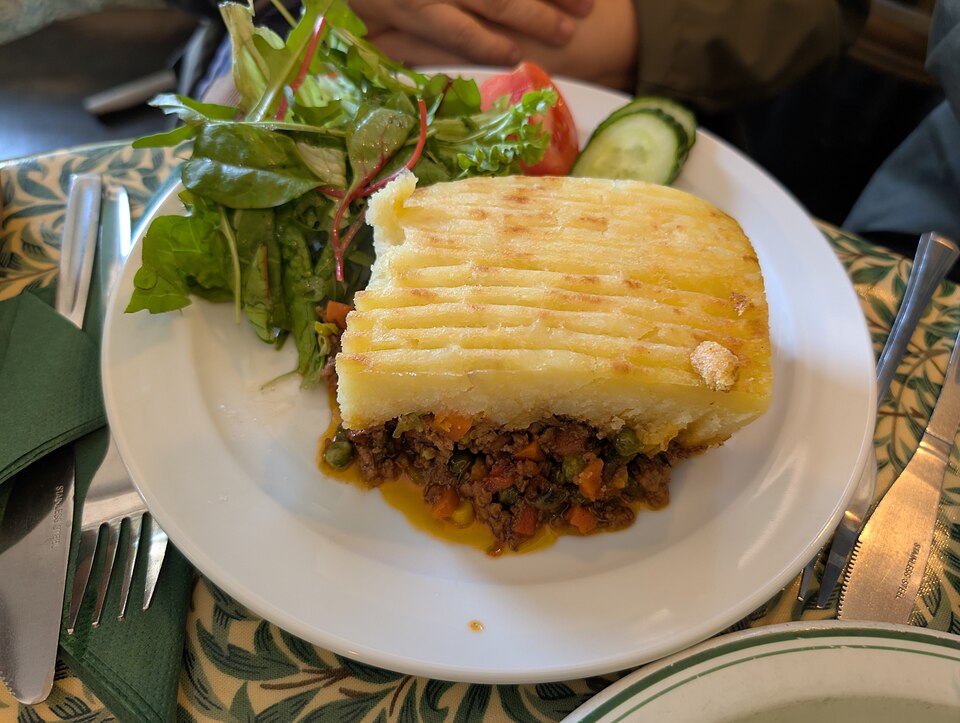 A slice of shepherd's pie with a golden mashed potato crust, served with salad