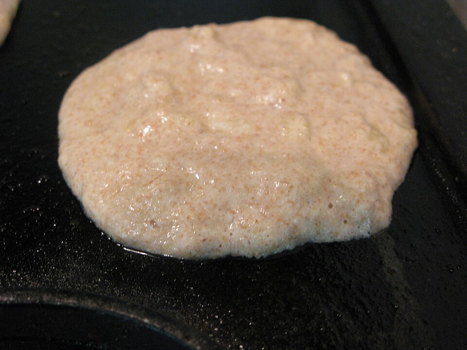 A thick pancake cooking on a griddle