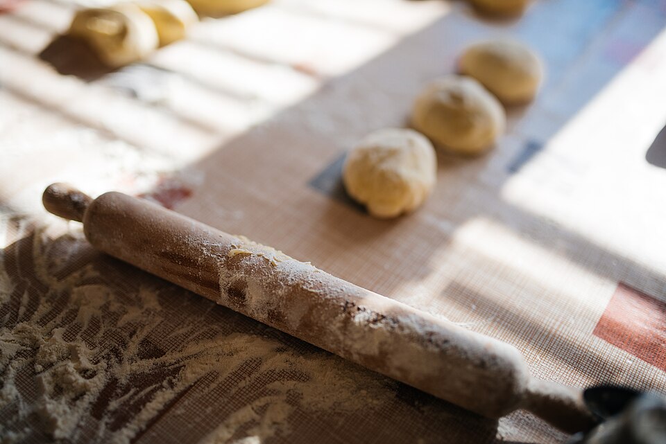 Dough and a wooden rolling pin on a floured board