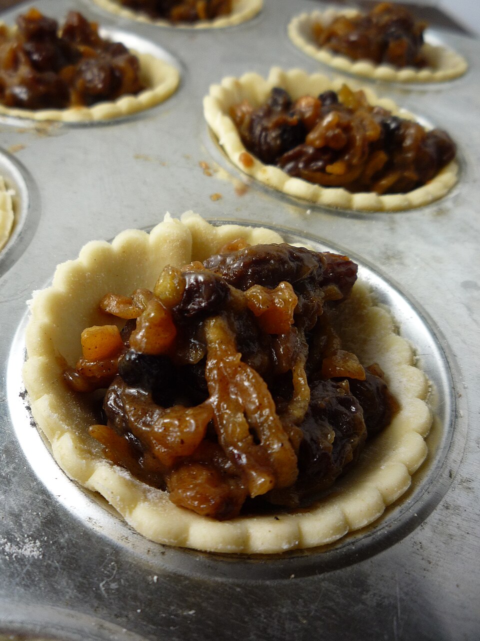 Pastry cases filled with mincemeat in a bun tin