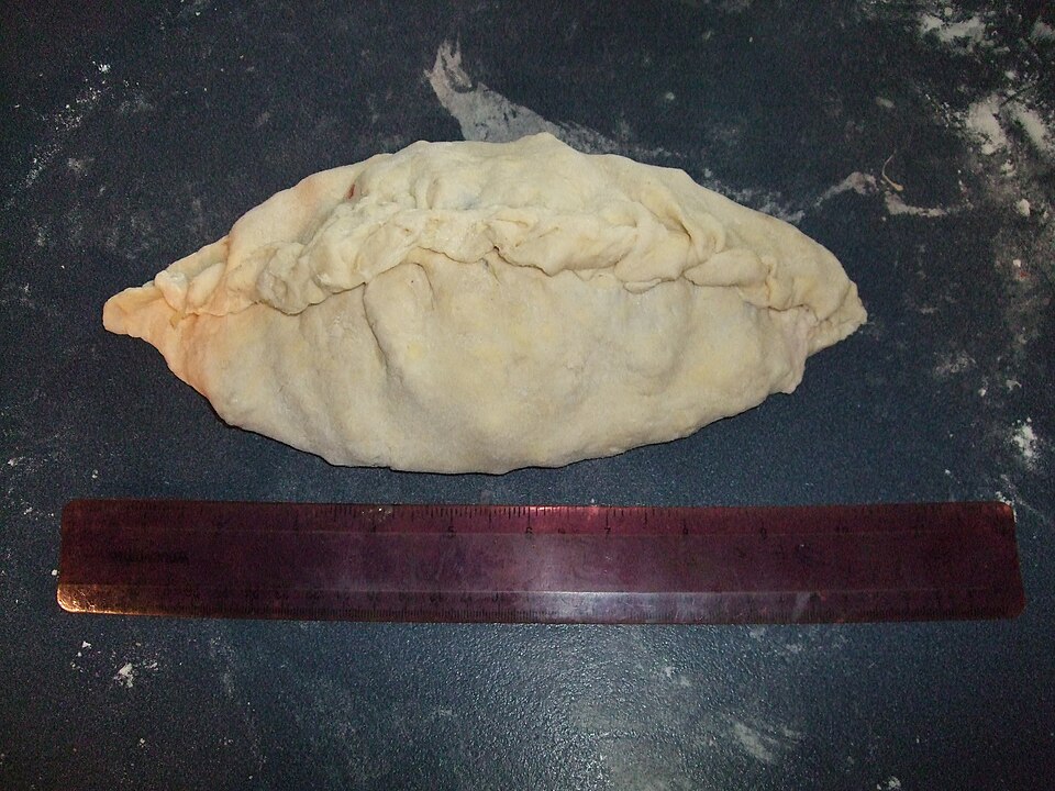 An unbaked pasty, folded and crimped