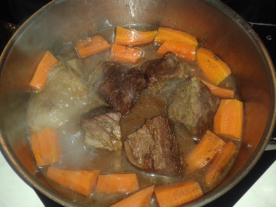 Chunks of beef stewing with carrots in a pan