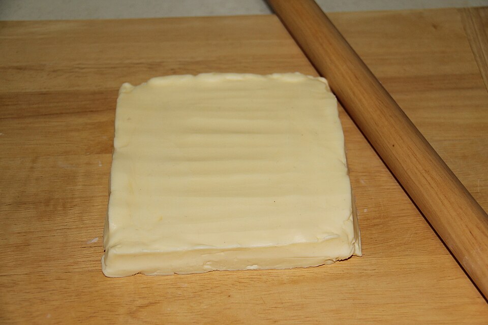 A sheet of pastry rolled out beside a rolling pin