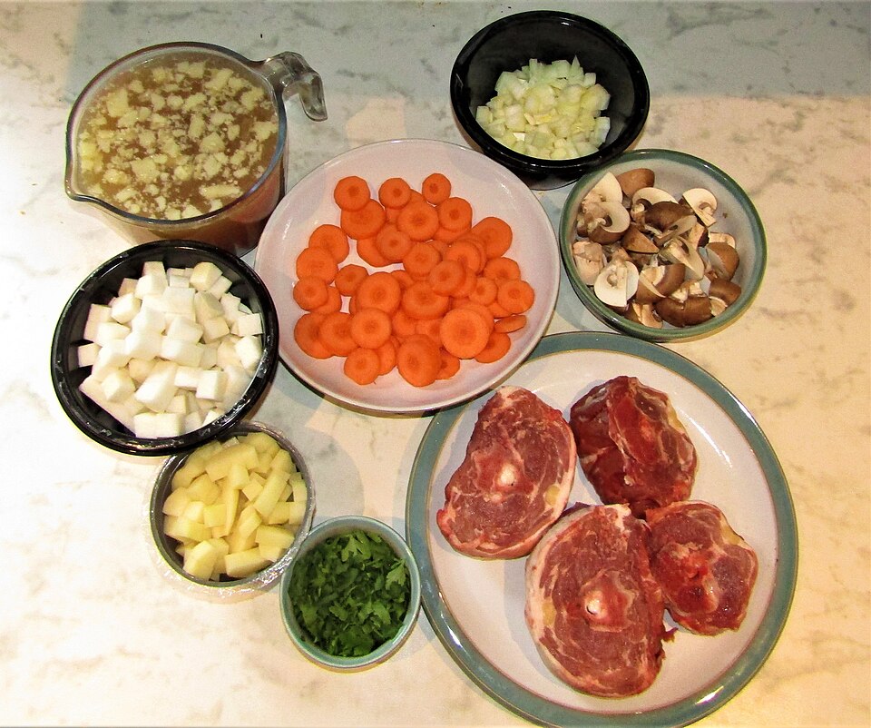 Ingredients for Irish stew laid out: lamb, potatoes, carrots, onion and herbs