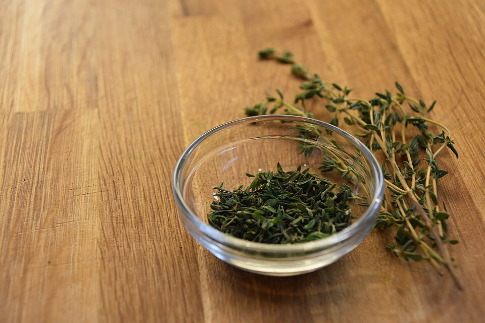Fresh thyme sprigs and chopped thyme in a small bowl