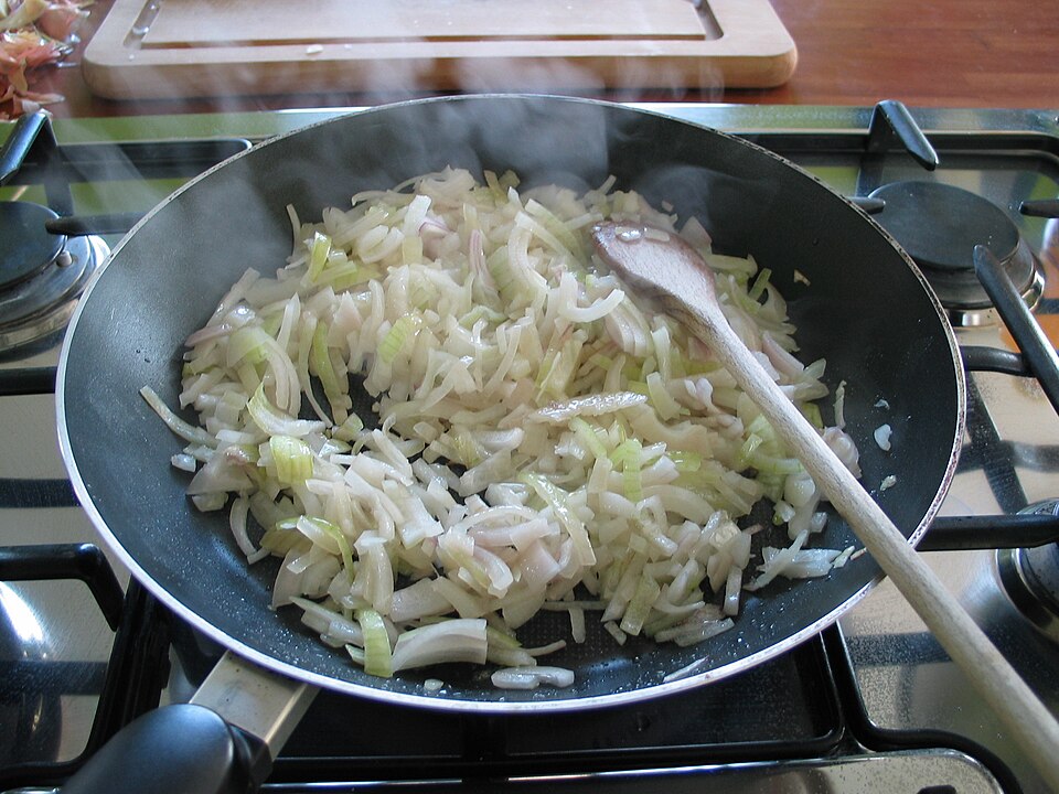 Sliced onions softening in a frying pan