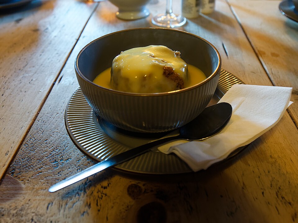 Sticky toffee pudding served in a bowl with custard