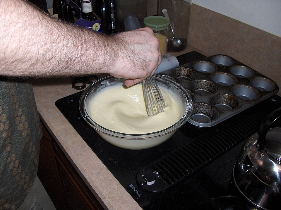 Whisking batter beside a heated tin