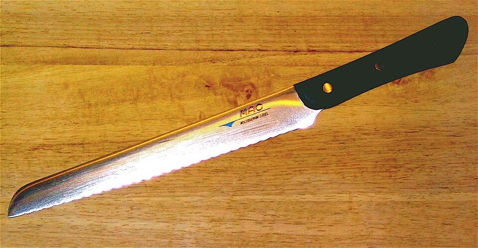 A serrated bread knife on a wooden board