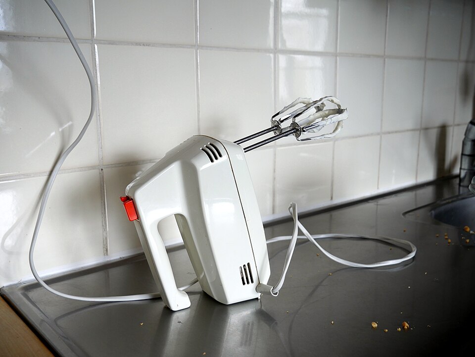 An electric hand mixer resting on a kitchen worktop