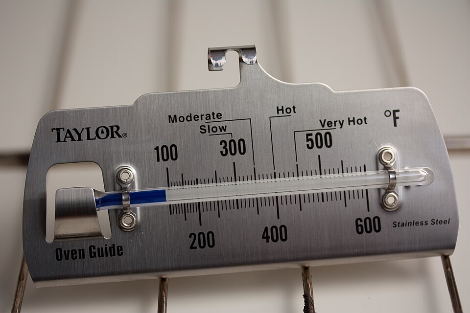 An oven thermometer hanging on an oven shelf