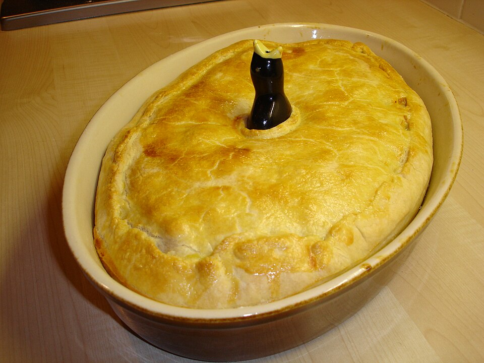 A pie with a blackbird pie funnel poking through the crust