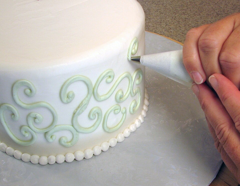 Piping buttercream decoration onto a cake