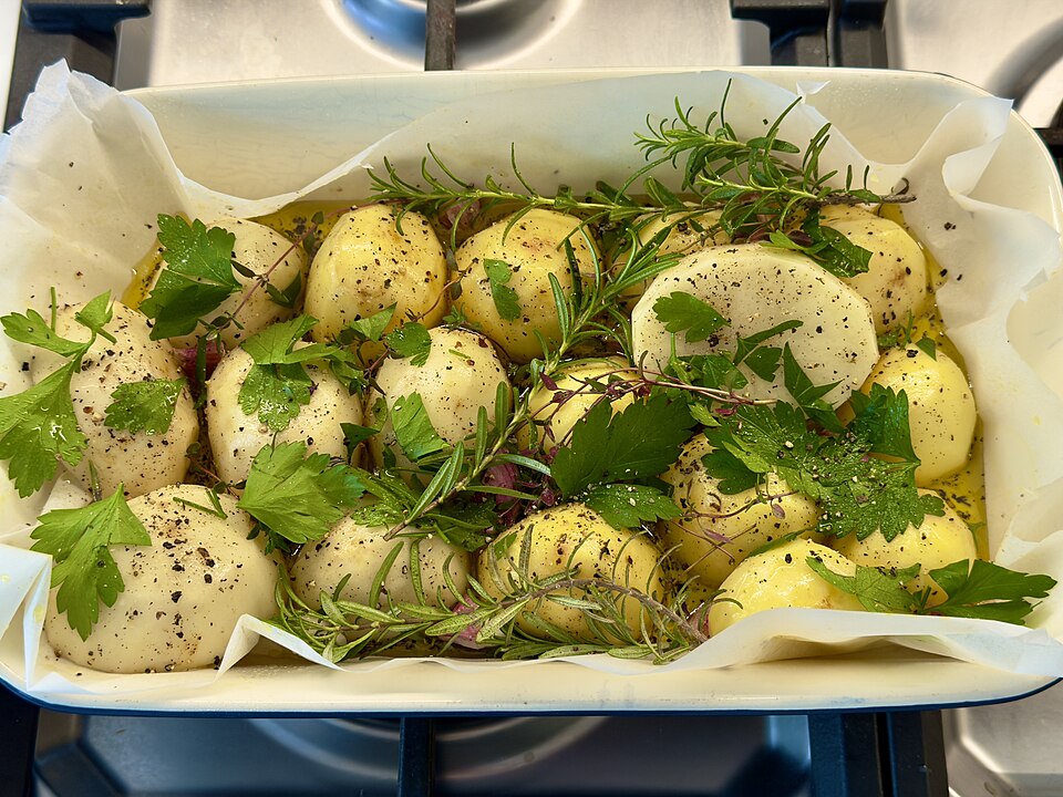 Potatoes with rosemary in a roasting tin, ready for the oven