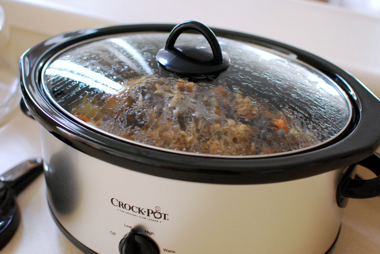 An oval slow cooker with a stew cooking under the glass lid