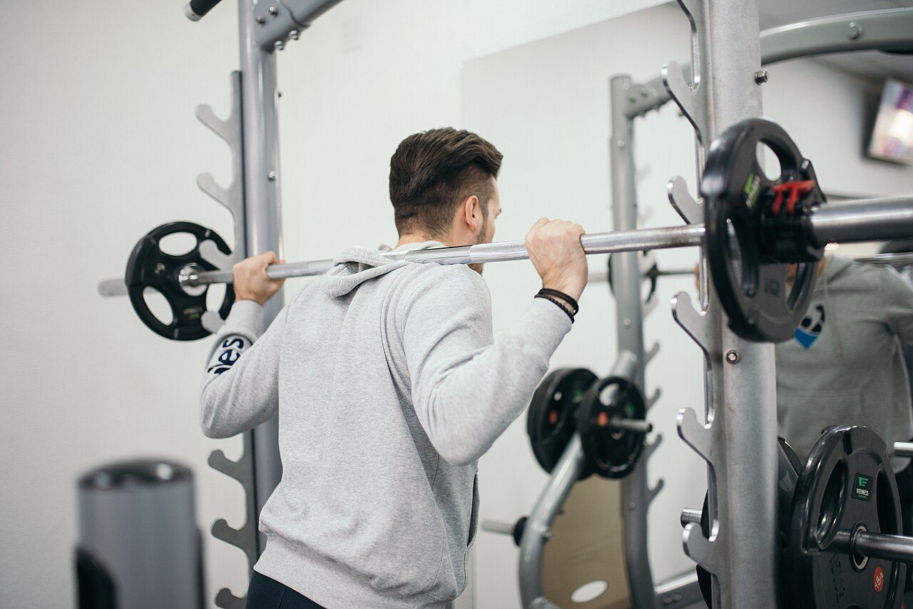 Man doing a barbell squat in a gym