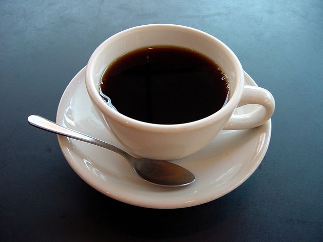 Cup of black coffee on a saucer with a spoon