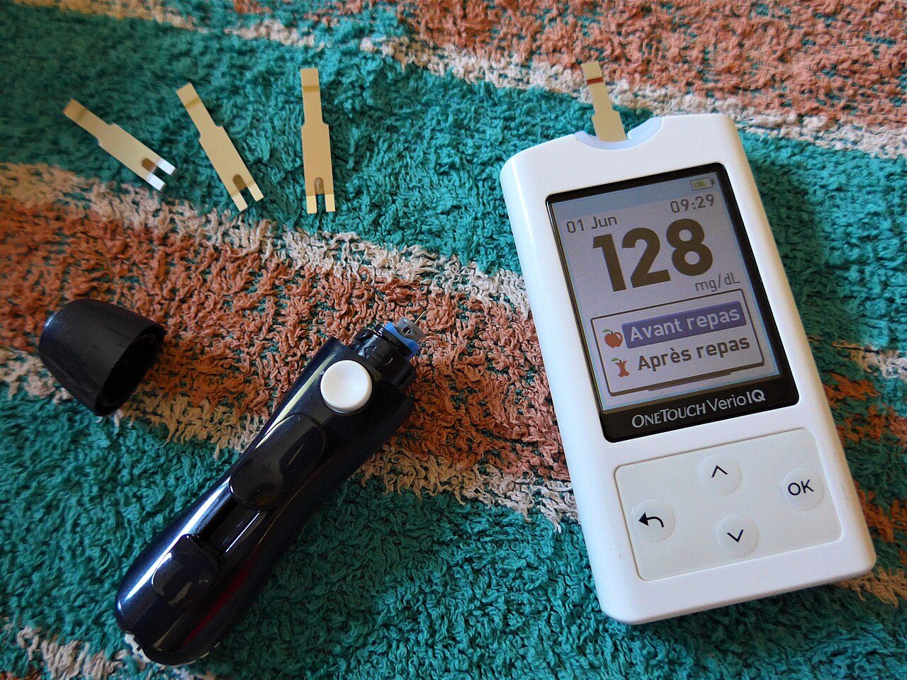 Blood glucose meter showing a reading, with a lancing device
