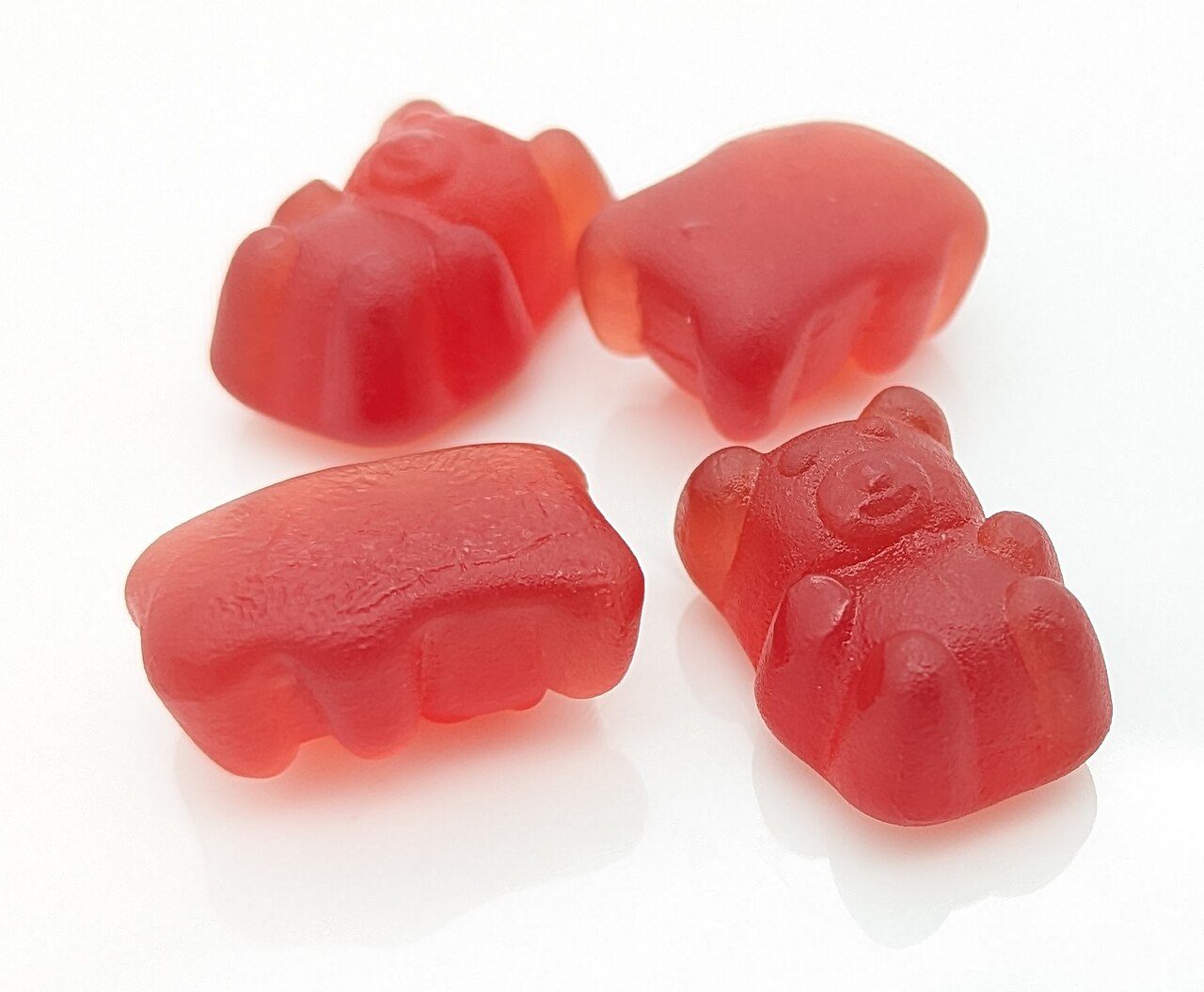 Four red gummies on a white background
