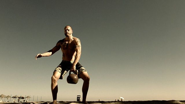 Man swinging a kettlebell outdoors