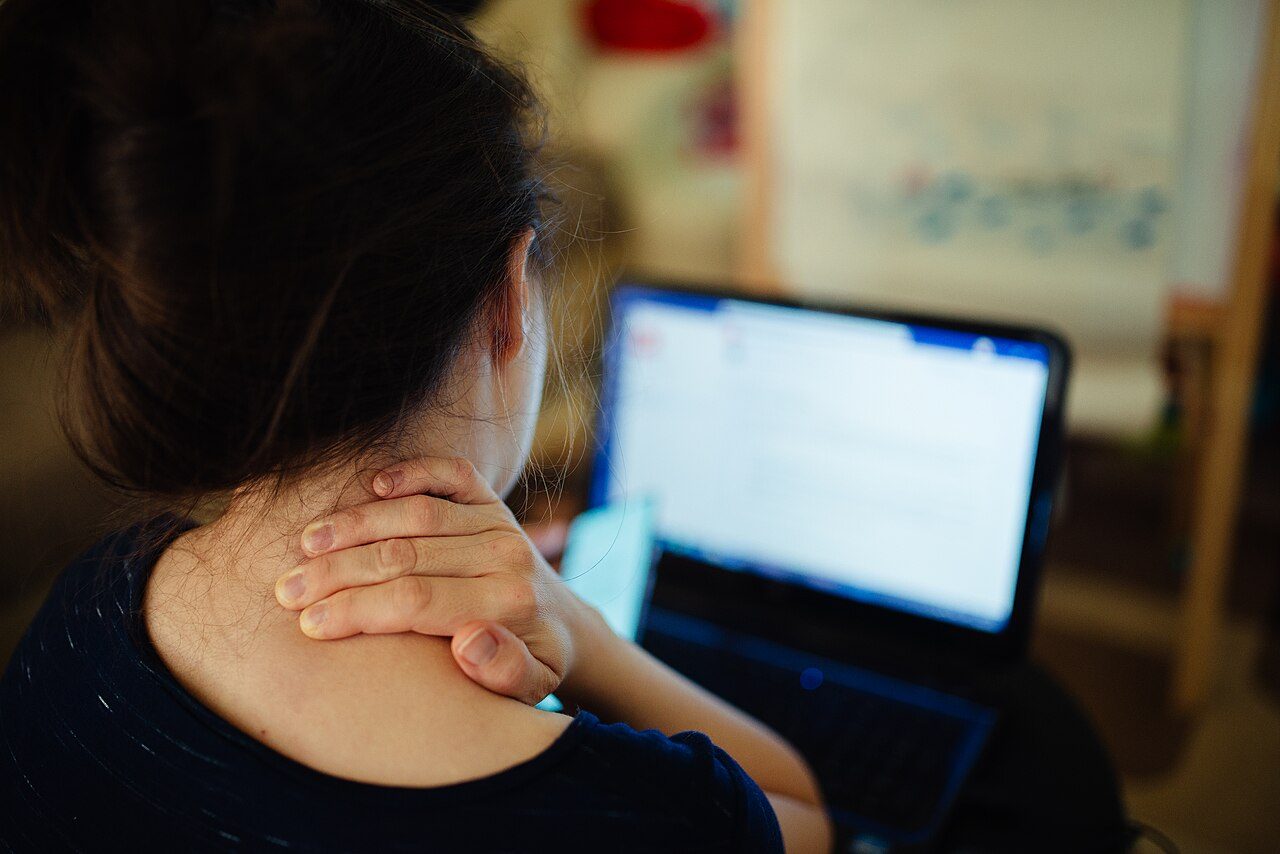 Woman holding her neck while working at a laptop